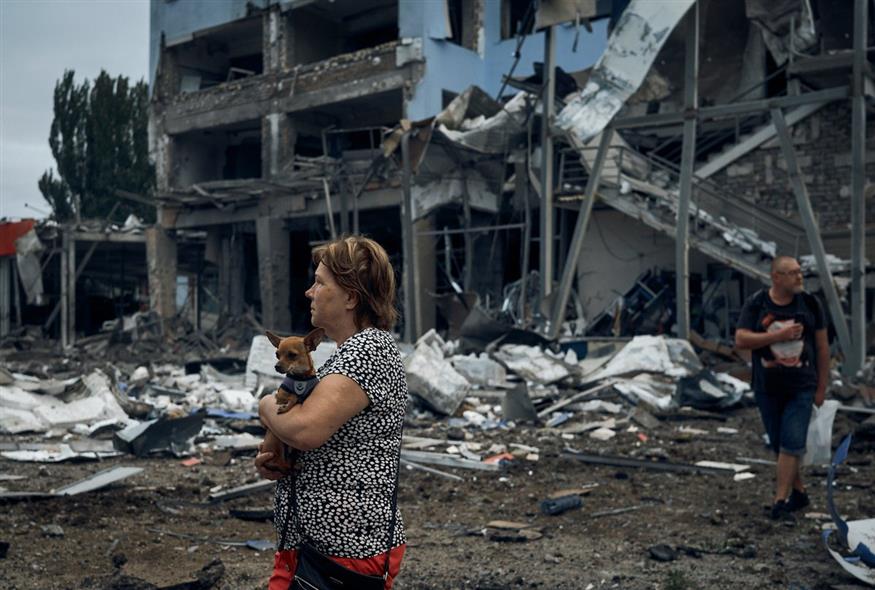 Μια γυναίκα κρατά έναν σκύλο μετά τους ρωσικούς βομβαρδισμούς στο Mykolaiv της Ουκρανίας / AP Photo/Kostiantyn Liberov