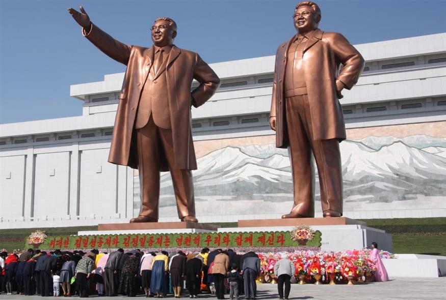 Βορειοκορεάτες υποκλίνονται στα αγάλματα του Κιμ Ιλ-σουνγκ (αριστερά) και του Κιμ Γιονγκ-ιλ.
