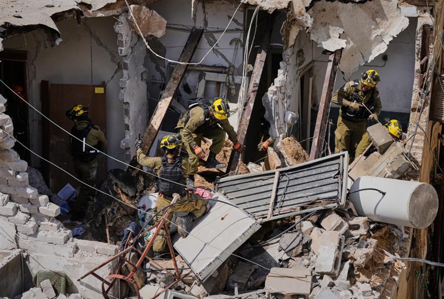 Οι ισραηλινές δυνάμεις ασφαλείας επιθεωρούν την περιοχή που χτυπήθηκε από ιρανικό πύραυλο στη Ντιμόνα, στο νότιο Ισραήλ (AP)