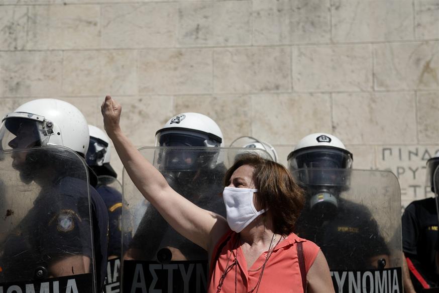 Διαδηλώτρια στο Σύνταγμα, με φόντο τα ΜΑΤ (EUROKINISSI/ΔΗΜΗΤΡΟΠΟΥΛΟΣ ΣΩΤΗΡΗΣ)