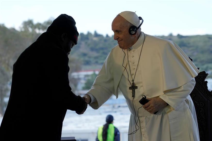 Ο Πάπας Φραγκίσκος σφίγγει το χέρι στον Christian Tango Mukaya, έναν 30χρονο αιτούντα άσυλο από το Κονγκό, κατά τη διάρκεια τελετής στον καταυλισμό προσφύγων Karatepe (Associated Press)