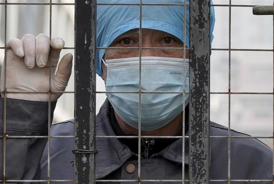 Εργαζόμενος στην Ουχάν παρακολουθεί από το εσωτερικό νοσοκομείου την άφιξη της ομάδας του ΠΟΥ (φωτογραφία αρχείου / Associated Press)