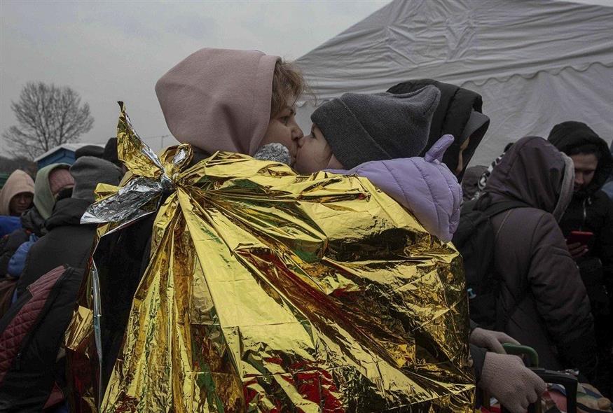 Γυναίκα αγκαλιάζει το παιδί της στα σύνορα Ουκρανίας - Πολωνίας (Associated Press)
