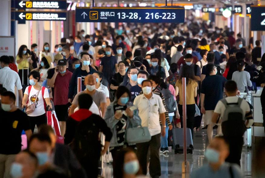 Επιβάτες που φορούν μάσκες προσώπου για να προστατευτούν από τον κορονοϊό περπατούν κατά μήκος μιας αίθουσας του διεθνούς αεροδρομίου Haikou Meilan στο Haikou της επαρχίας Χαϊνάν της νότιας Κίνας / AP Photo/Mark Schiefelbein
