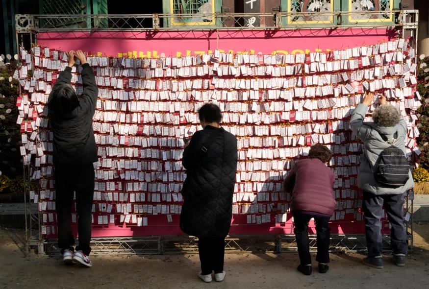Γονείς κρεμούν σημειωματάκια με ευχές για τα εξεταζόμενα παιδιά τους σε βουδιστικό ναό της Σεούλ (Ahn Young-joon/AP)