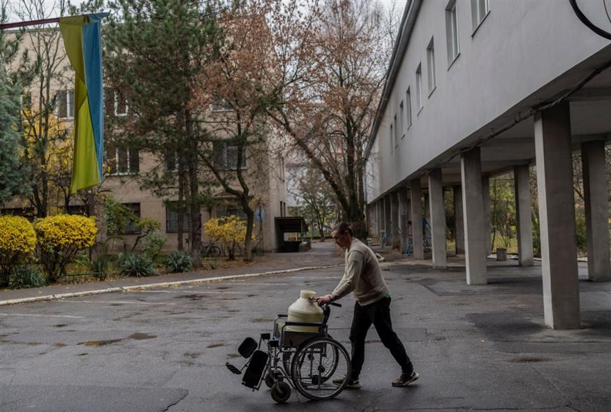 Ένα άνδρας κουβαλά ένα μπιτόνι με νερό με αναπηρικό καροτσάκι στη Χερσώνα (AP Photo/Bernat Armangue)