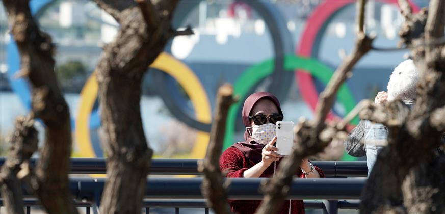 Γυναίκα με προστατευτική μάσκα φωτογραφίζεται με φόντο τους Ολυμπιακούς κύκλους (AP Photo/Eugene Hoshiko)