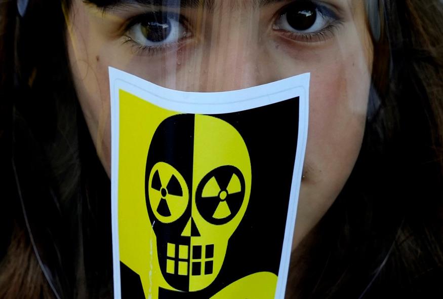 Ένα κορίτσι με αντιπυρηνικό αυτοκόλλητο σε μάσκα εμφανίζεται κατά τη διάρκεια διαδήλωσης / AP Photo/Petros Karadjias