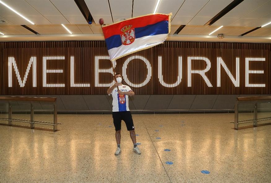 Οπαδός του Νόβακ Τζόκοβιτς κυματίζει σημαία της Σερβίας στην αίθουσα αφίξεων στο αεροδρόμιο της Μελβούρνης./ copyright Ap Photos