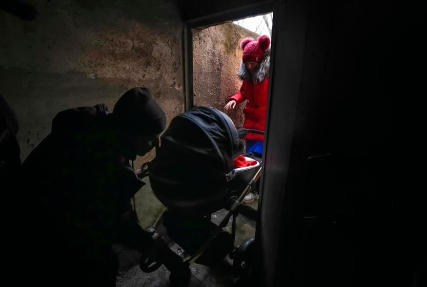 Ένα ζευγάρι μπαίνει σε καταφύγιο με ένα μωρό σε καροτσάκι κατά τη διάρκεια ρωσικών βομβαρδισμών έξω από τη Μαριούπολη της Ουκρανίας / AP Photo/Sergei Grits
