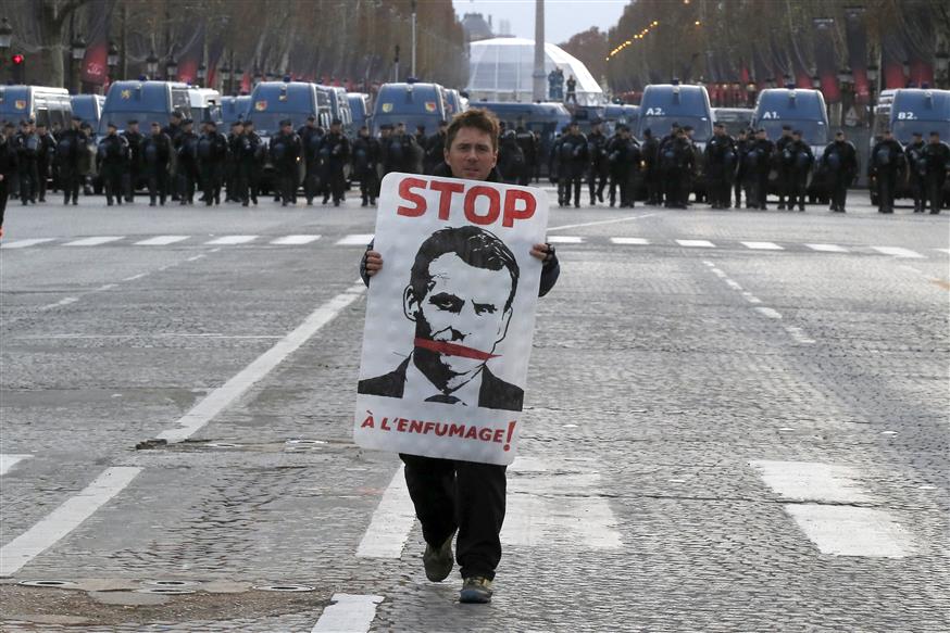 Διαδηλωτής κρατά στα χέρια του αφίσα του Μακρόν  (AP Photo/Michel Euler)