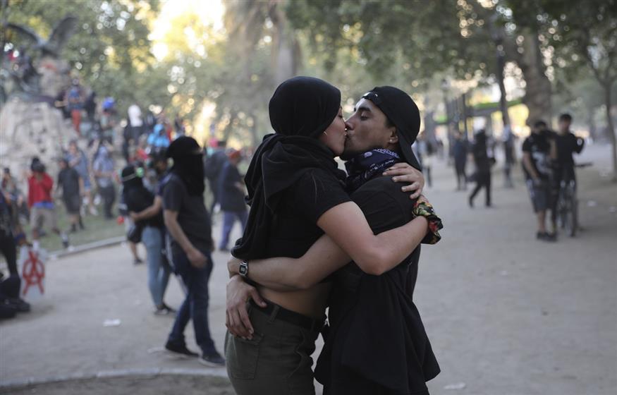 Διαδηλωτές φιλιούνται εν μέσω δακρυγόνων στη Χιλή (AP Photo/Rodrigo Abd)