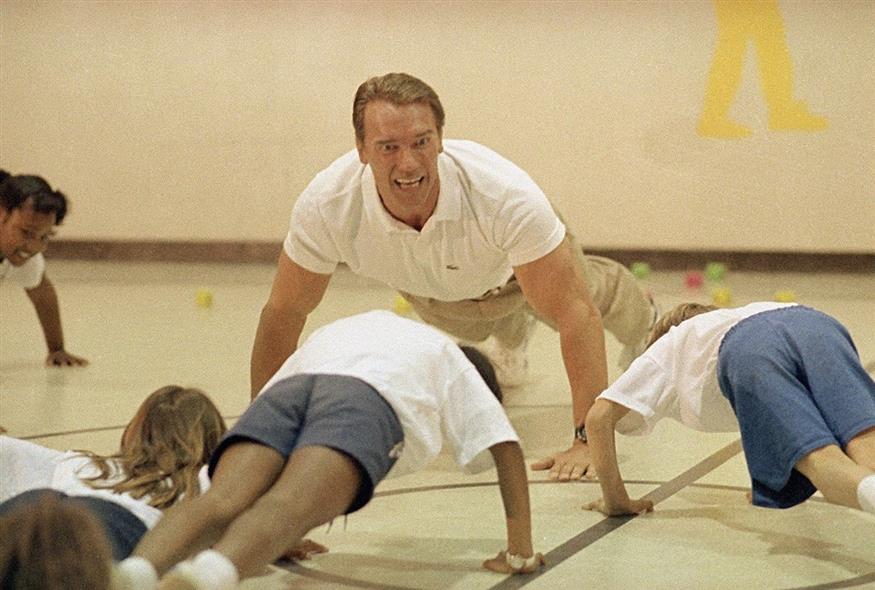 Ο Άρνολντ Σβαρτσενέγκερ καθοδηγεί μαθητές σχολείου του Άρκανσο να κάνουν πους απς (φωτογραφία αρχείου / Associated Press)
