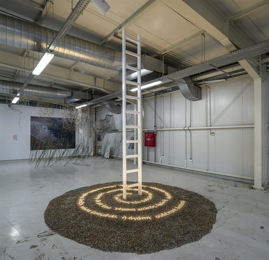 Κλαίρη Τσαλουχίδου - Χατζημηνά, Scala Paradisi «Η κυκλική κίνηση εδώ υποδηλώνει μια κατάσταση όχι μόνο πνευματική, αλλά και διαλογισμού», εξηγεί. «Όλη η σύνθεση στηρίζεται πάνω σε αυτό το στρώμα χαλικιού, που για την καλλιτέχνιδα λειτουργεί ως σχόλιο για τη γη — για την ανθρώπινη τέφρα, για την αρχή και το τέλος της ύπαρξης. Είναι μια ποιητική αναφορά στο από πού ερχόμαστε και πού τελικά επιστρέφουμε» αναφέρει ο κ Πράπογλου (Copyright: Christos Simatos)