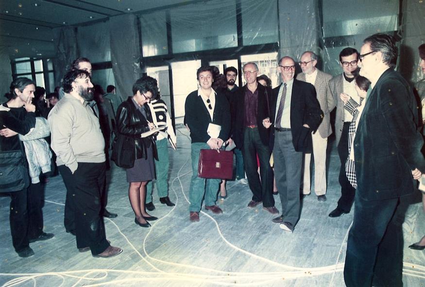 Ο Χρήστος Λαμπράκης με τον Θάνο Μικρούτσικο στην πρώτη συνέντευξη Tύπου για το Μέγαρο Μουσικής που ήταν ακόμα σχεδόν γιαπί. Η Μικέλα Χαρτουλάρη κρατά σημειώσεις. Τριγύρω όλοι οι δημοσιογράφοι του τότε πολιτιστικού ρεπορτάζ