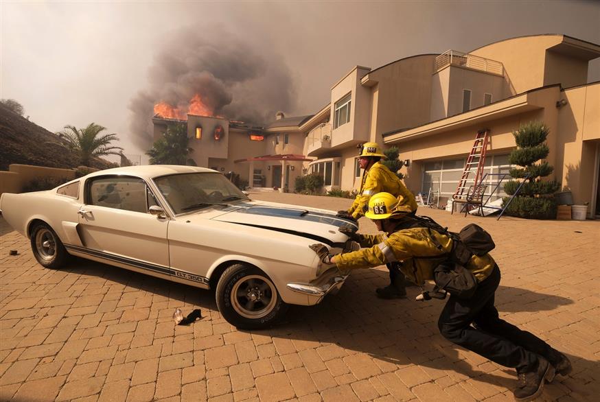 Εικόνα με τους πυροσβέστες να προσπαθούν να γλιτώσουν ένα αυτοκίνητο πριν περάσει η καταστροφική πυρκαγιά (AP)