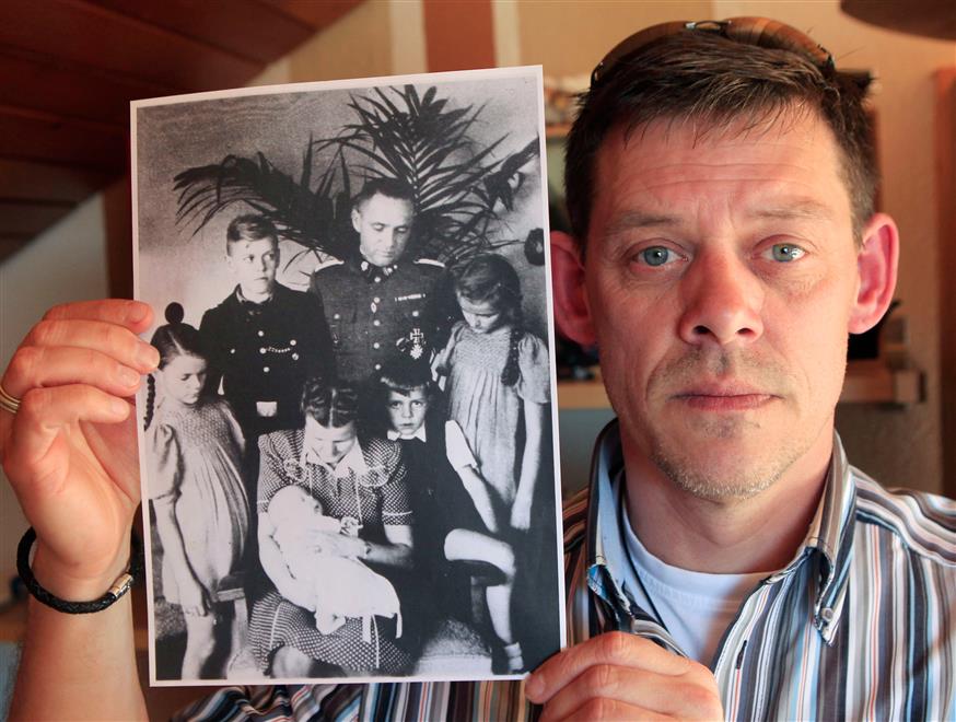 Ο Ράινερ Ες δείχνει μια φωτογραφία της οικογένειάς του, όπου εικονίζεται και ο Ρούντολφ. Ο Ράινερ ήταν 12 ετών όταν ανακάλυψε ότι ο παππούς του ήταν ένας από τους χειρότερους δολοφόνους στην Ιστορία.
