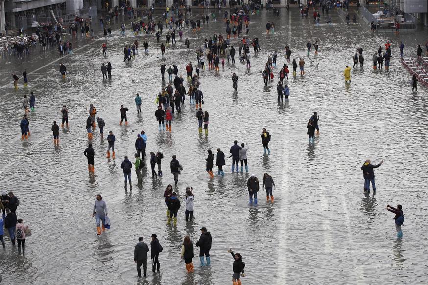 Tourists cross flooded St. Mark's Square in Venice (AP Photo/Luca Bruno)