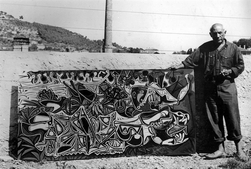O Πάμπλο Πικάσο ποζάρει δίπλα σε έναν από τους πίνακές του το 1950 (Associated Press)