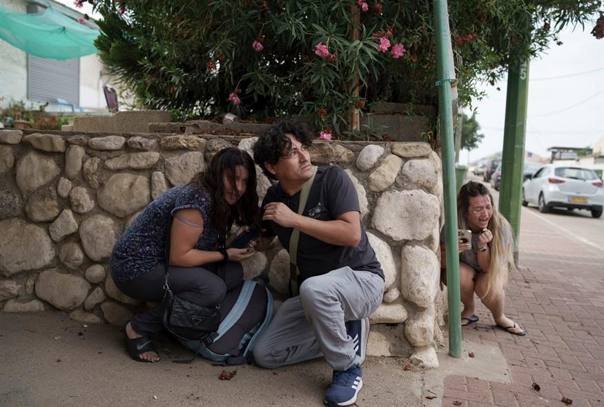 Ισραηλινοί προστατεύονται από τα πυραύλους που εκτοξεύτηκαν από τη Λωρίδα της Γάζας στο Ασκελόν  (AP Photo/Leo Correa)