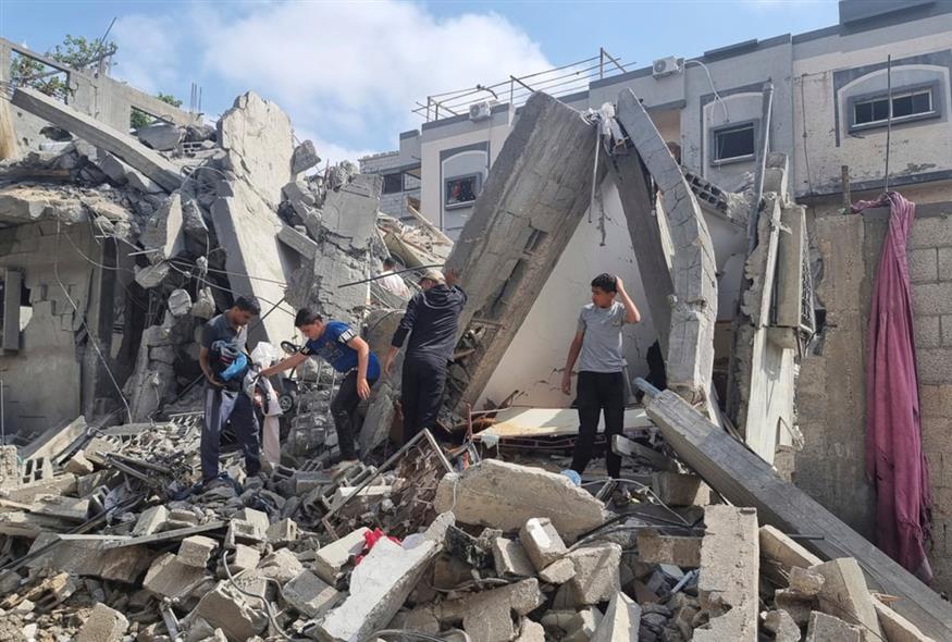 Παλαιστίνιοι κοιτούν τις καταστροφές που έχει υποστεί το σπίτι τους μετά από βομβαρδισμό/AP