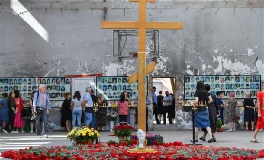 Φωτογραφίες των δολοφονημένων παιδιών, εκπαιδευτικών, γονέων, στους τοίχους του Γυμναστηρίου στο 1ο Σχολείο του Μπεσλάν. Στο κέντρο ένας ξύλινος σταυρός και γύρω του λουλούδια (φωτ.: interfax-russia.ru)