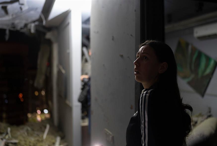Μια Ουκρανή κοιτάει συγκλονισμένη το σπίτι των γειτόνων της που βομβαρδίστηκε (AP Photo/Jae C. Hong)