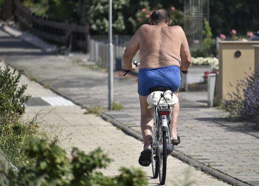 Ολλανδός, με ελάχιστα ρούχα, προσπαθεί να αντιμετωπίσει το (διαρκές) κύμα καύσωνα (AP Photo/Martin Meissner)