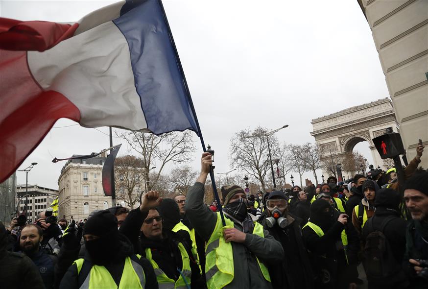 Διαδηλωτές κρατούν τη Γαλλική σημαία μπροστά από τον Αψίδα του Θριάμβου (AP Photo/Thibault Camus)