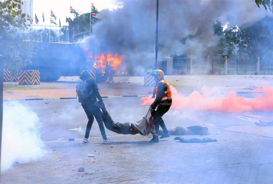 διαδηλωτές στην Κένυα κουβαλούν άνδρα που έχει δεχθεί σφαίρα/AP