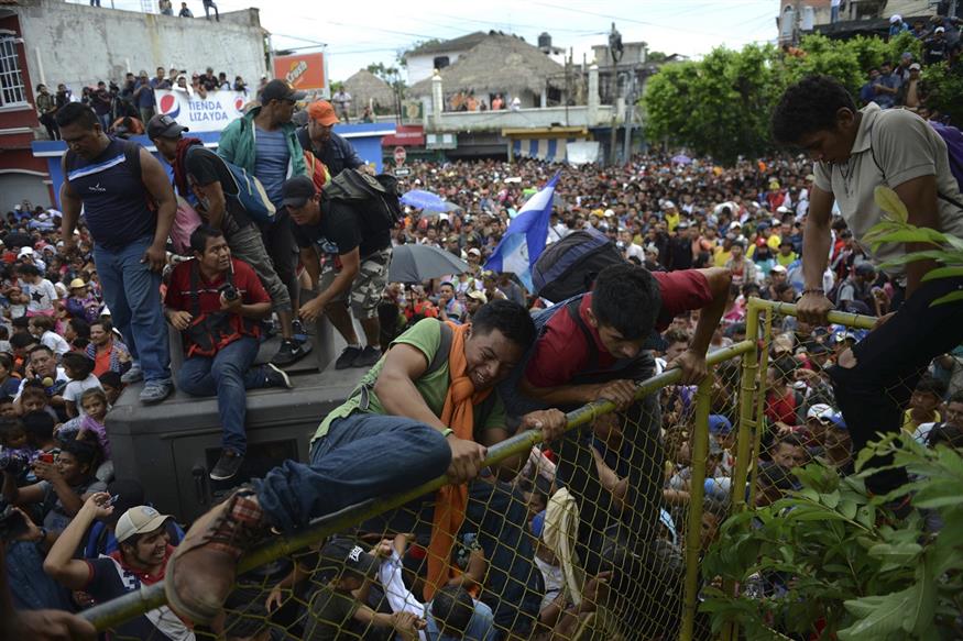 Νεαροί άνδρες µε χαµόγελα ελπίδας στα πρόσωπά τους εµφανίζονται να πηδούν τον φράχτη στην περιοχή Τεκούν Ουµάν (AP Photo/Oliver de Ros)