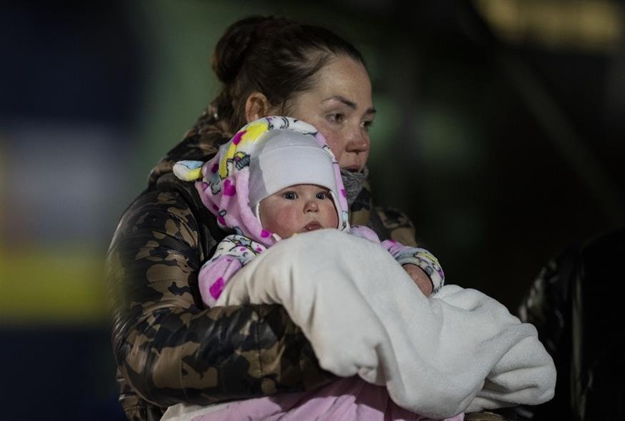 Ουκρανή πρόσφυγας περνάει με το μωρό της τα σύνορα με την Πολωνία το Σάββατο, 12 Μαρτίου (Associated Press)
