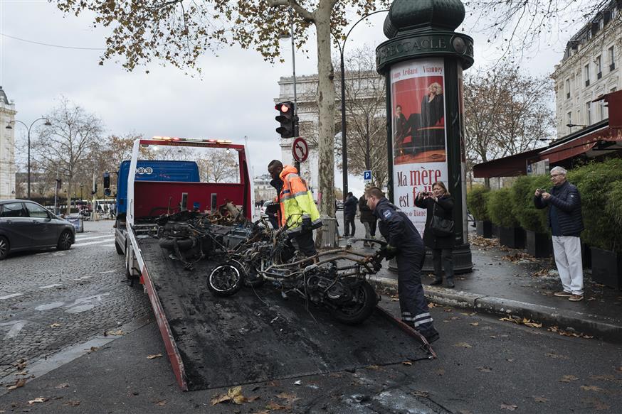 Εργάτες απομακρύνουν κατεστραμένες μηχανές μετά τα χθεσινά επεισόδια στο Παρίσι (AP Photo/Kamil Zihnioglu)