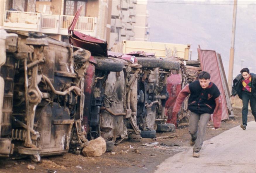 Δύο παιδιά από τη Βοσνία προσπαθούν να προστατευτούν από τα πυρά ελεύθερων σκοπευτών στο Σαράγεβο το 1993 (Rikard Larma/AP)