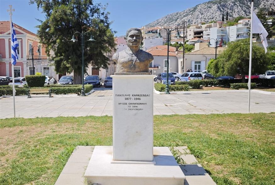 Η προτομή του Παντελή Καρασεβδά στην κεντρική πλατεία του Αστακού περιστοιχίζεται από σημαίες της Ελλάδας και της Ολυμπιακής Επιτροπής / φωτογραφίες Kώστας Ασημακόπουλος ethnos.gr