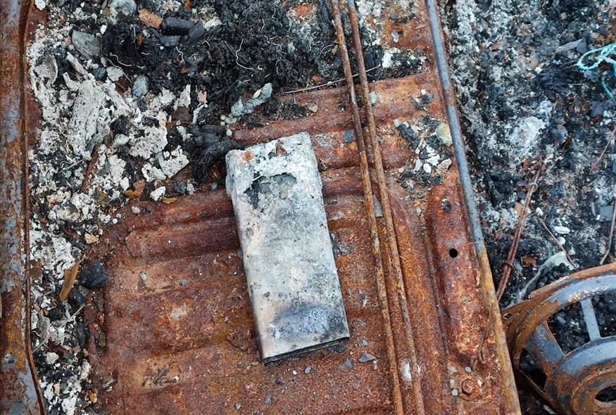 Ένα καρβουνιασμένο κινητό τηλέφωνο βρίσκεται στο καμένο αυτοκίνητο