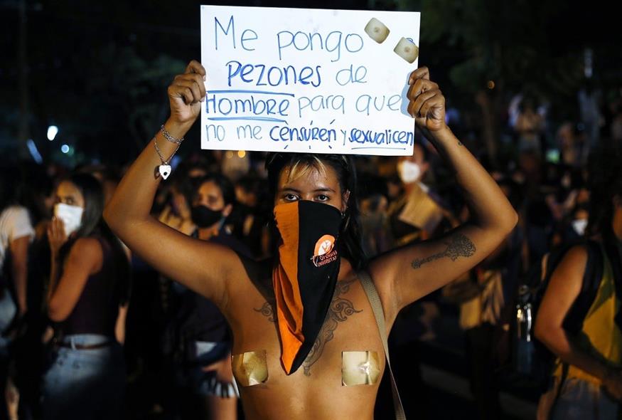 Γυναίκα δια διαδήλωση για την Παγκόσμια Ημέρα της Γυναίκας στην Παραγουάη κρατάει πλακάτ που γράφει «Φοράω ανδρικές θηλές για να μη με λογοκρίνουν» (Associated Press)