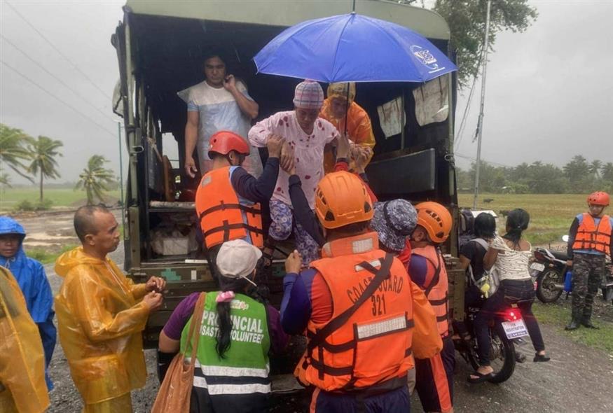 Διασώστες της Ακτοφυλακής των Φιλιππίνων βοηθούν κατοίκους να εκκενώσουν το Σαμπλάιαν, στην επαρχία Οξιντένταλ Μιντόρο (AP/PHILIPPINE COAST GUARD)