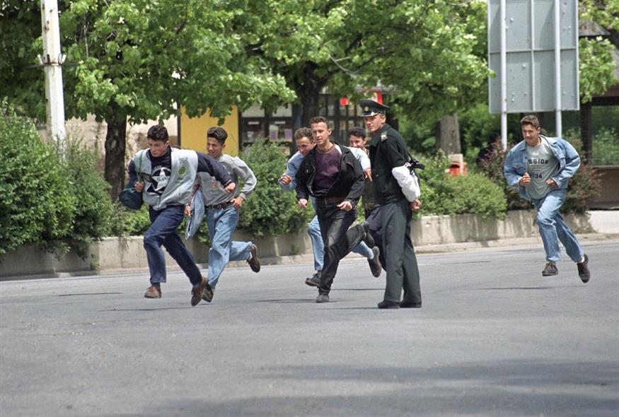 Κάτοικοι του Σαράγιεβο και ένας Βόσνιος τροχονόμος τρέχουν να προφυλακτούν από πυρά ελεύθερων σκοπευτών προς το μέρος τους το 1995 (Jerome Delay/AP)
