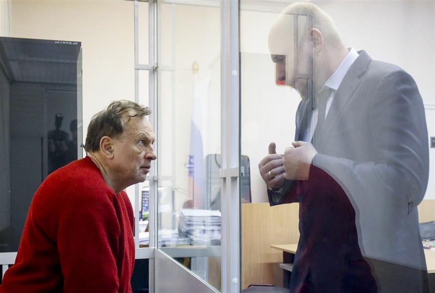 Ο ιστορικός φορά κίκκινη μπλούζα, ο δικηγόρος του στέκει έξω από τον κλωβό  (AP Photo/Dmitri Lovetsky)