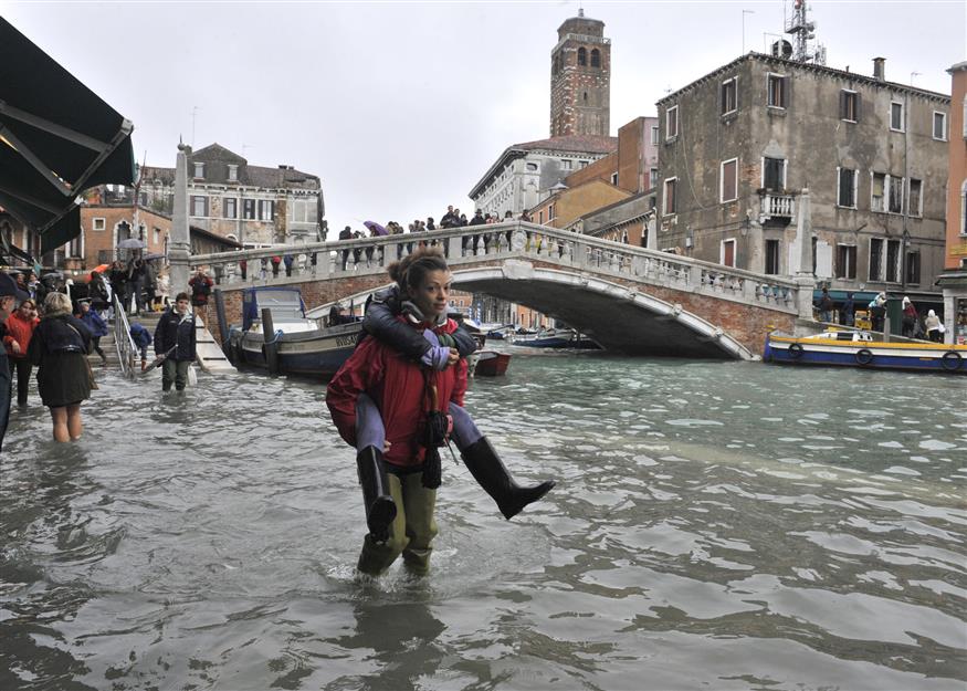 Τρέχουν να προστατευτούν από τη βροχή οι τουρίστες στη Βενετία (AP)