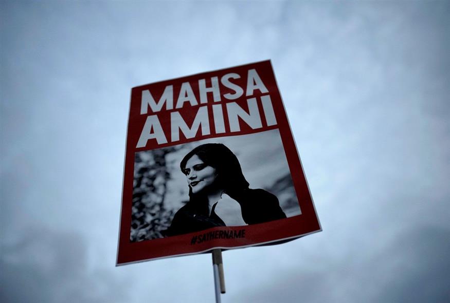 Μια γυναίκα κρατάει ένα πλακάτ με τη φωτογραφία της Mahsa Amini / AP Photo/Markus Schreiber