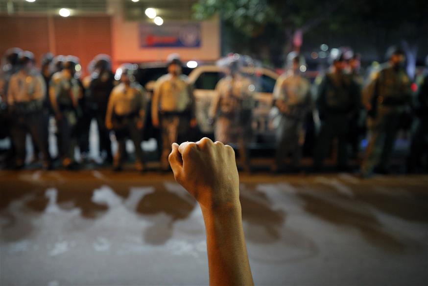 Υψωμένη γροθιά διαδηλωτή μπροστά από αστυνομικούς (AP Photo/John Locher)