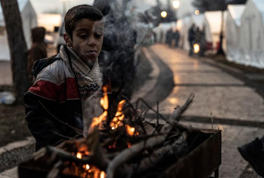 Παιδί προσπαθεί να ζεσταθεί σε καμπ για σεισμόπληκτους στην Τουρκία (AP Photo/Mustafa Karali)