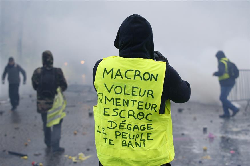 Στο γιλέκο του ο διαδηλωτής χαρακτηρίζει τον Μακρόν ως κλέφτη, ψεύτη και του ζητά να παραιτηθεί (AP Photo/Thibault Camus)